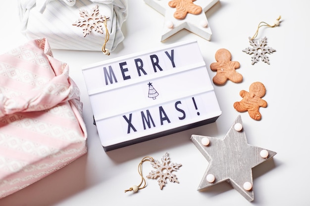 Inscription de la boîte à lumière Joyeux Noël cadeaux dans le style japonais furoshiki et biscuits au pain d'épice