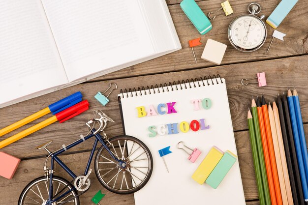 Inscription du bloc-notes de chronomètre de modèle de bicyclette de retour à l'école et d'autres articles de papeterie sur une table en bois