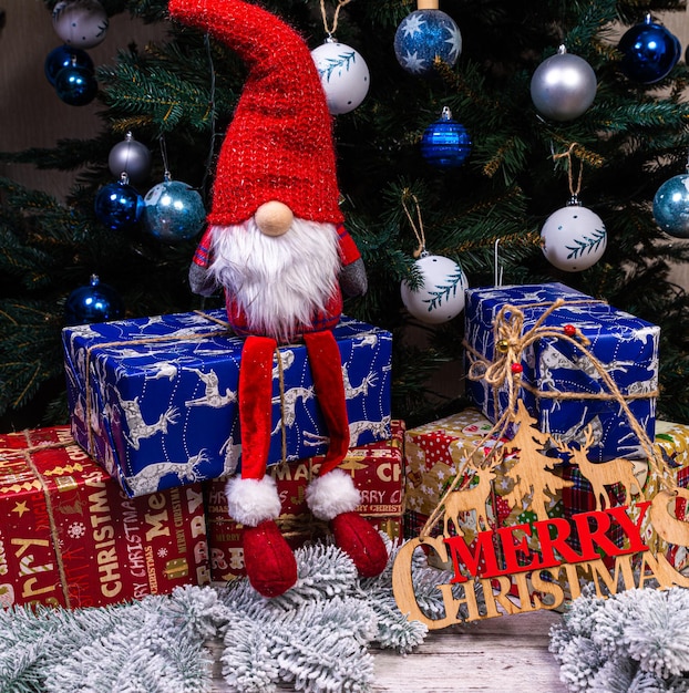 L'inscription hiver d'un arbre sur un Nouvel An Sur les branches d'épinette sur fond de neige se trouvent des boules blanches bleues du Nouvel An avec des cônes d'épinette et une boîte avec un cadeau de Noël
