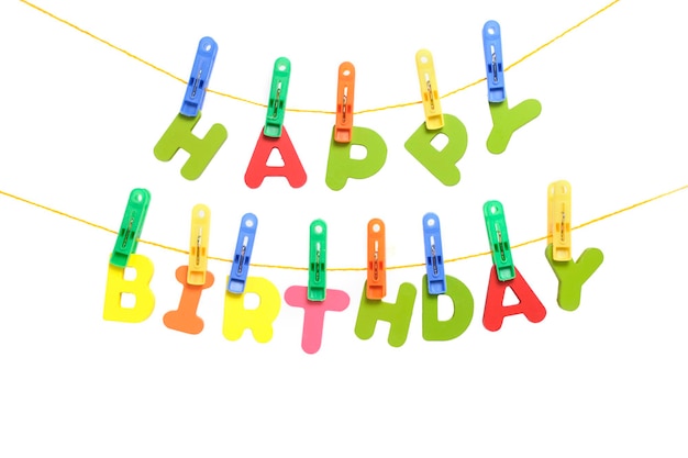 L'inscription joyeux anniversaire en lettres multicolores est accrochée par des pinces à linge comme une guirlande