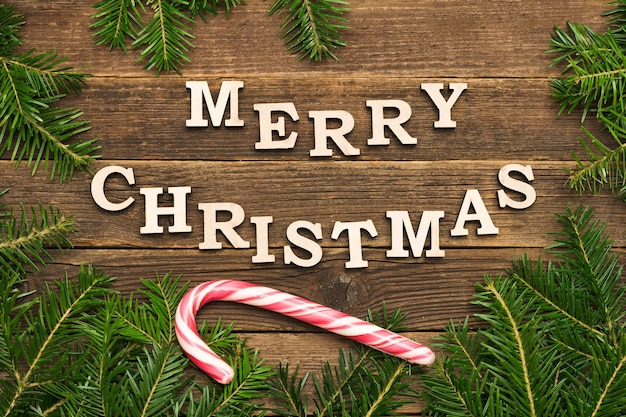 Inscription Joyeux Noël sur un fond en bois Cadre de bâton de sucette de branches de sapin
