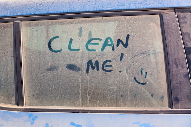 L'inscription Nettoie-moi sur une voiture sale avec un sourire