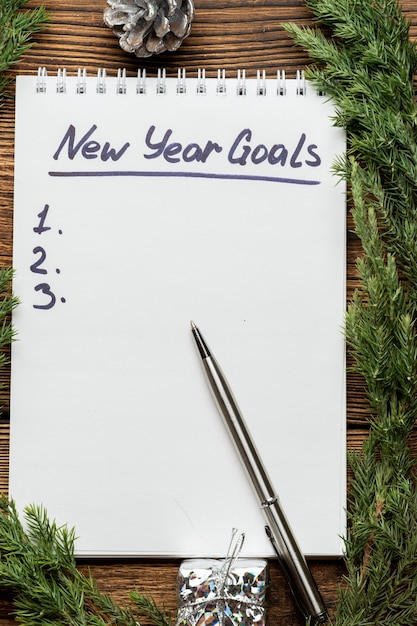 Photo inscription des objectifs du nouvel an dans le cahier avec des branches d'épinette et des jouets d'arbre de noël