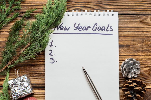 Photo inscription des objectifs du nouvel an dans le cahier avec des branches de sapin, d'épinette et de sapin de noël