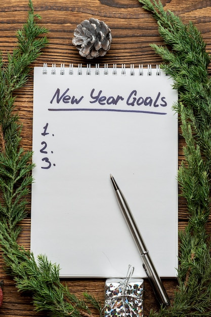 Photo inscription des objectifs du nouvel an dans le cahier avec des branches de sapin, d'épinette et de sapin de noël