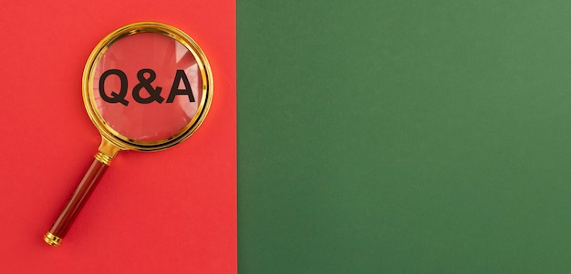 Inscription Qna sur bannière rouge et verte à travers une loupe. Acronyme d'assurance qualité. Notion Q. Questions et réponses. Arrière-plan avec espace de copie.