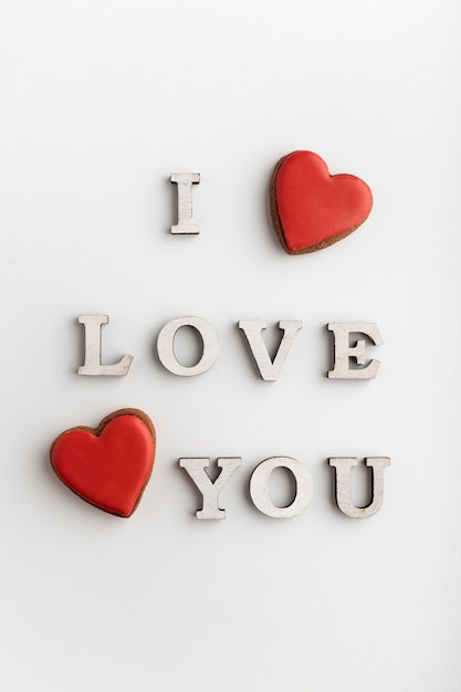 Inscription romantique je t'aime et biscuits de pain d'épice en forme de coeur rouge, fond blanc. La Saint-Valentin.