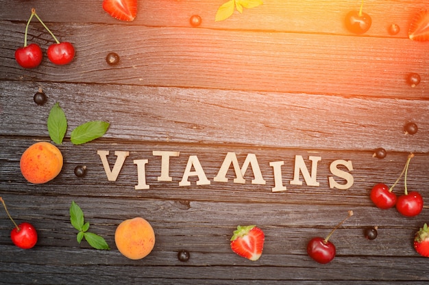 Inscription Vitamines et fruits. Fond en bois noir Concept alimentaire