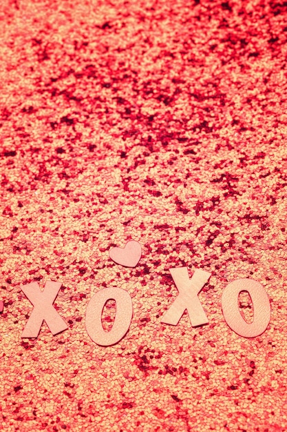 L'inscription xo xo paillettes et coeurs sur fond rose