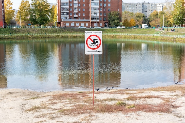 Photo inscrivez-vous interdisant de nager dans un étang à proximité de bâtiments résidentiels