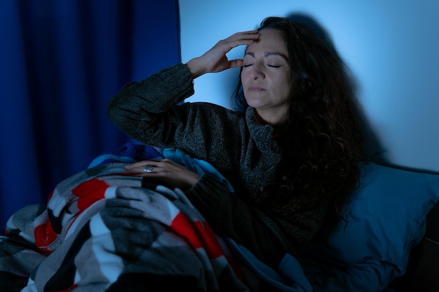 Insomnie Femme déprimée assise dans son lit la nuit, elle ne peut pas dormir à cause de l'insomnie