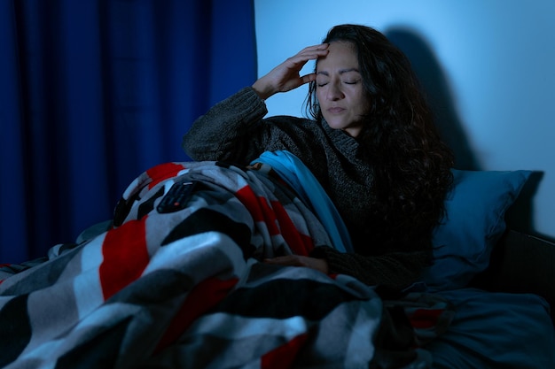 Insomnie Femme déprimée assise dans son lit la nuit, elle ne peut pas dormir à cause de l'insomnie