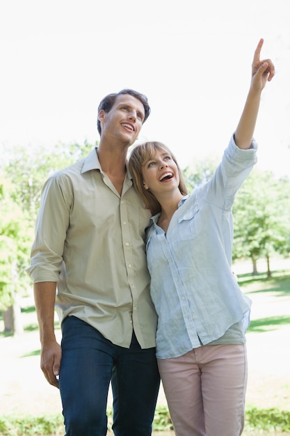 Insouciant couple debout dans le parc avec une femme pointant