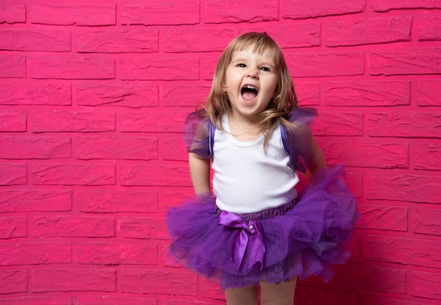 Insouciante Mignonne Petite Fille En Jupe Tutu Riant Aux éclats De Rire Sur Fond Rose.