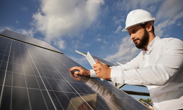 Inspecteur masculin concentré vérifiant des panneaux solaires au chantier de construction