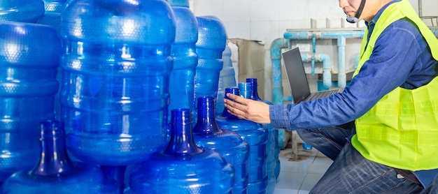 Inspecteur de la qualité dans une usine vérifiant les gallons d'eau bleue avant expédition pour contenir de l'eau potable