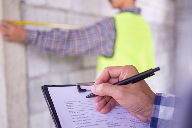 Photo les inspecteurs vérifient le projet de maison auquel la propriété a été affectée pour travailler avec l'ingénieur entrepreneur. de plus, notez les détails du travail pour être prêt et correct selon le modèle.