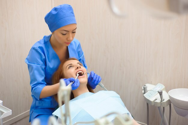 Inspection dentaire en clinique. Médecin en uniforme vérifiant les dents de la patiente dans une clinique dentaire.