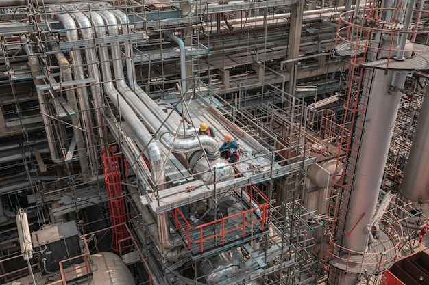 Photo inspection par un travailleur masculin des longs tuyaux en acier et du coude du tuyau dans le ventilateur d'aile de l'usine de pétrole de la station pendant la valve de la raffinerie de l'échangeur de chaleur de la pipeline