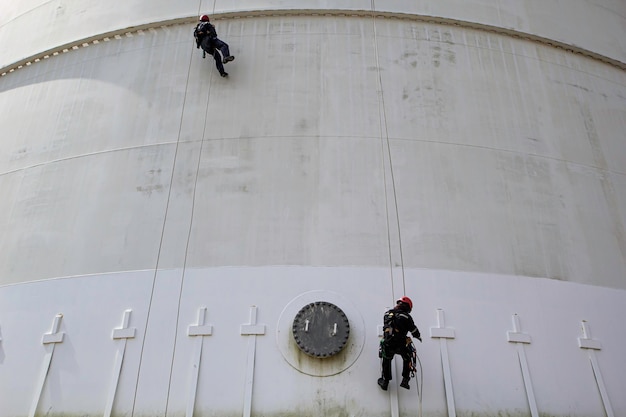 Inspection de sécurité de la hauteur d'accès à la corde du travailleur masculin de l'industrie des réservoirs de pétrole et de gaz de stockage d'épaisseur