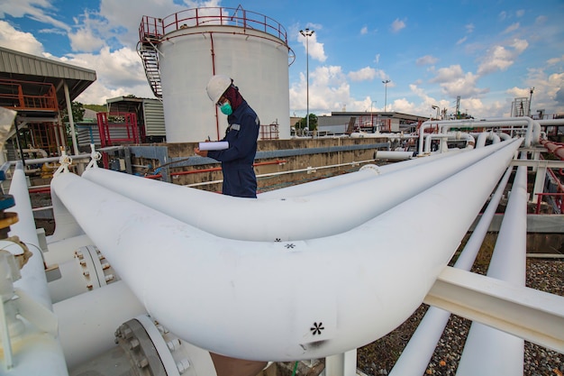 Photo inspection d'un travailleur masculin sur de longs tuyaux en acier et un coude de tuyau dans l'usine pétrolière de la station pendant la vanne de raffinerie de l'industrie pétrolière et gazière du pipeline de contrôle visuel.