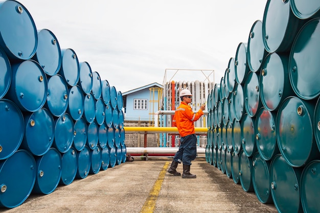 L'inspection des travailleurs masculins enregistre des barils de stock d'huile de tambour bleu et vert horizontal ou chimique pour l'industrie.