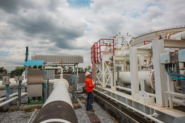 Inspection des travailleurs de sexe masculin dans les longs tuyaux en acier et le coude de tuyau dans l'usine pétrolière de la station pendant la vanne de raffinerie du pipeline d'enregistrement de contrôle visuel