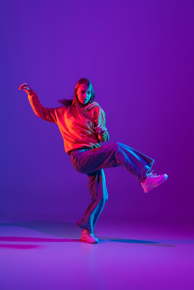 Photo inspiré. garçon sportif élégant dansant le hip-hop dans des vêtements élégants sur fond coloré à la salle de danse à la lumière du néon. culture jeunesse, mouvement, style et mode, action. portrait lumineux à la mode.