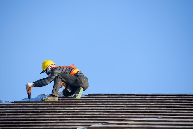 Installateur de toiture Installez le toit de la maison qui est un toit de tuiles de céramique sur le chantier de construction