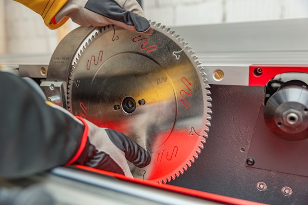 Installation du cercle de disque de scie. L'artisan installe la lame de scie circulaire sur la machine à bois. Entretien et réglage de la scie circulaire.