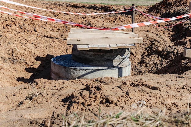 Installation d'un puits en béton armé pour l'approvisionnement en eau et l'assainissement sur le chantier Anneaux de puits préparés pour le montage