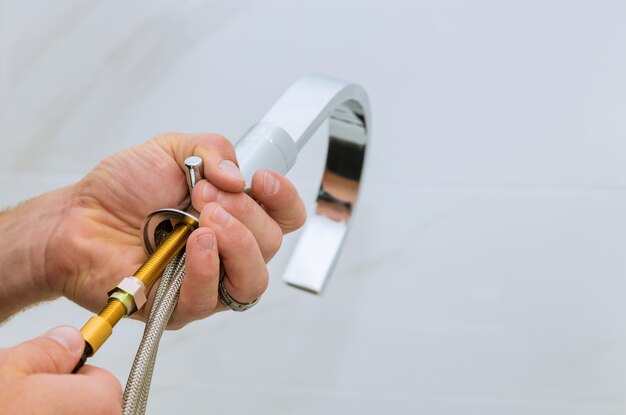 Installation d'un robinet d'eau dans le plombier de la salle de bain au travail dans la salle de bain