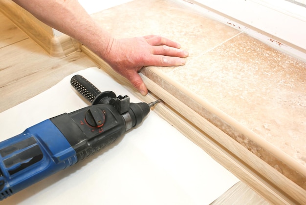 Installation de seuil à l'intérieur. Percer dans les mains. Travaux de rénovation dans l'appartement.