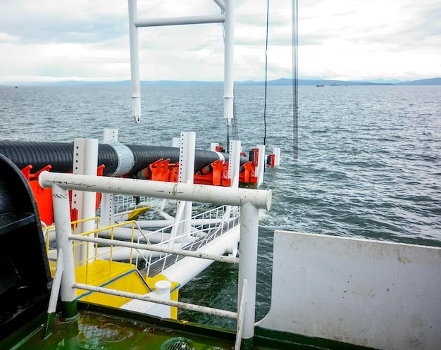 Photo installation de tuyaux avec une grue de barge à tuyaux près du rivage descente du pipeline jusqu'à un fond épuisant avec la barge à tubes installation du pipeline de gaz sous-marin