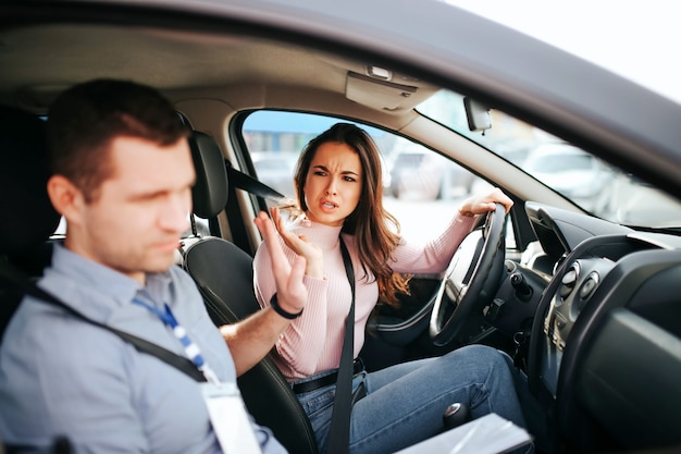 Instructeur automobile masculin prend l'examen avec la jeune femme