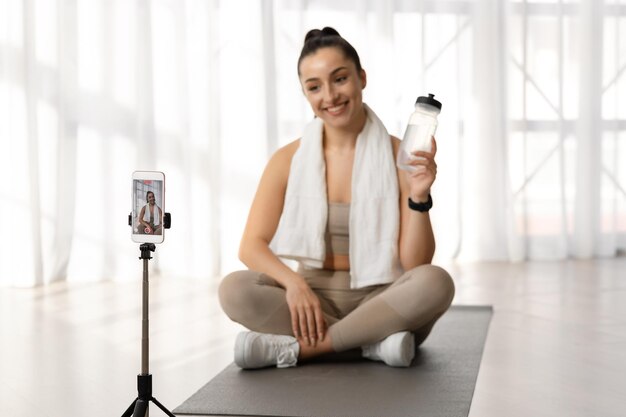 Instructeur de conditionnement physique féminin recommandant la diffusion d'eau potable depuis la maison