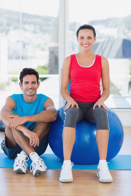 Instructeur et femme souriante avec ballon d&#39;exercice au gymnase