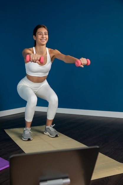 Photo instructeur de fitness féminin enseignant un cours à la maison avec tablette