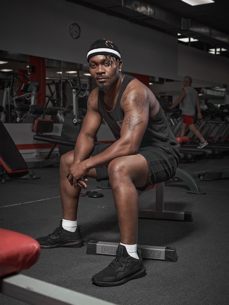 Instructeur de fitness masculin afro-américain de sport élégant assis sur un banc bel homme athlétique sur