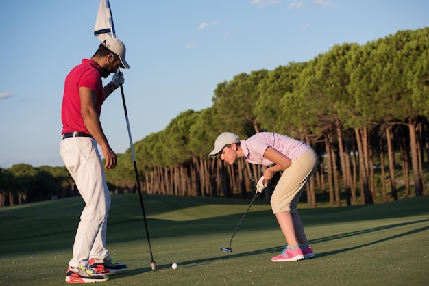 instructeur de golf masculin enseignant une joueuse de golf, entraîneur personnel donnant une leçon sur le terrain de golf