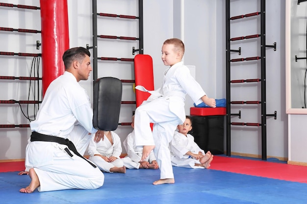 Instructeur de karaté masculin formant de petits enfants au dojo