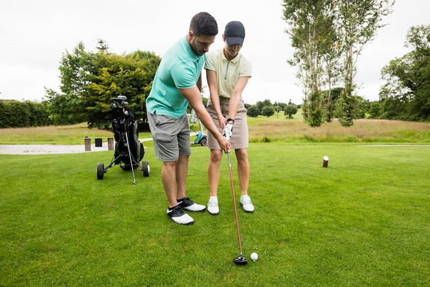 Instructeur masculin aidant la femme à apprendre le golf