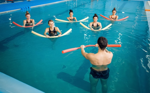 Instructeur masculin et groupe féminin, entraînement d'aquagym dans la piscine