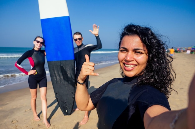 Instructeur de surf et deux filles surfeurs débutants faisant un portrait seifie sur smartphone caméra à Goa Inde