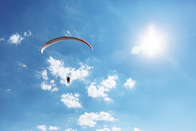 Instructeur tandem parapente rouge avec un touriste volant dans le ciel avec des nuages par une journée ensoleillée