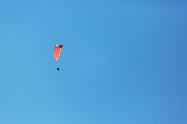 Photo instructeur tandem parapente rouge avec un touriste volant dans le ciel avec des nuages par une journée ensoleillée