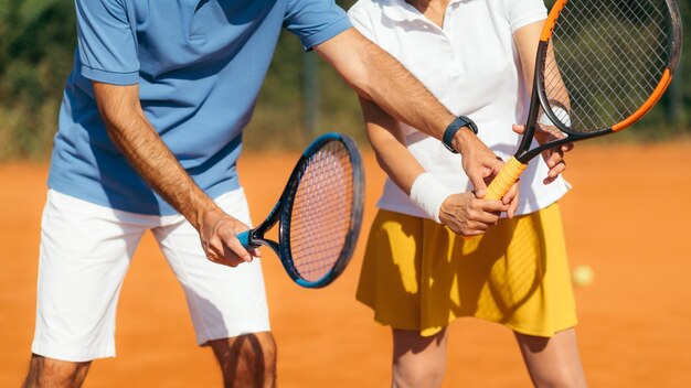 Instructeur de tennis avec une femme âgée sur terre battue Femme ayant une leçon de tennis