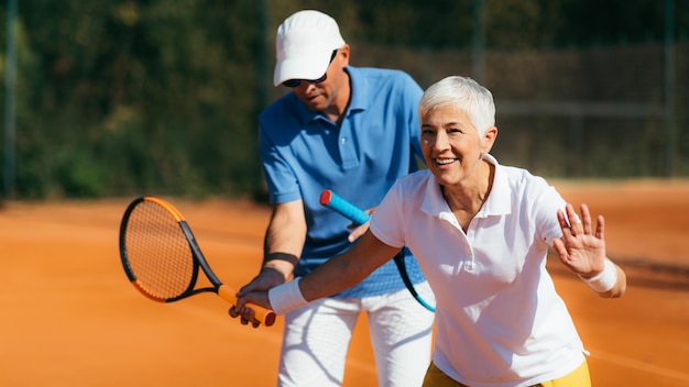 Instructeur de tennis avec une leçon d'entraînement de tennis pour femme senior