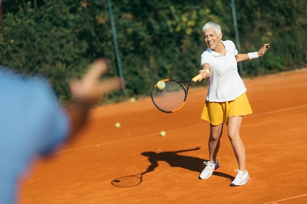 Instructeur de tennis avec une leçon d'entraînement de tennis pour femme senior