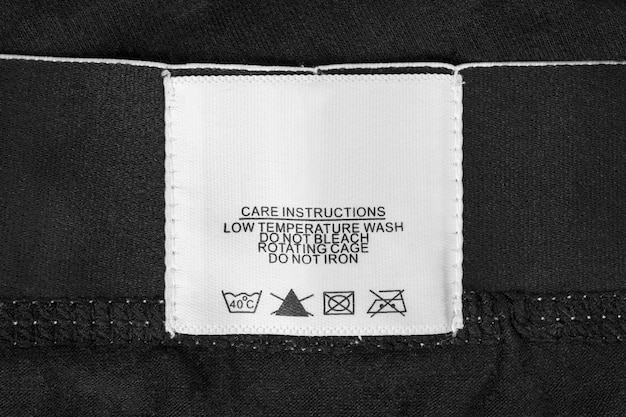 Instructions d'entretien étiquette de vêtements sur fond de tissu noir gros plan